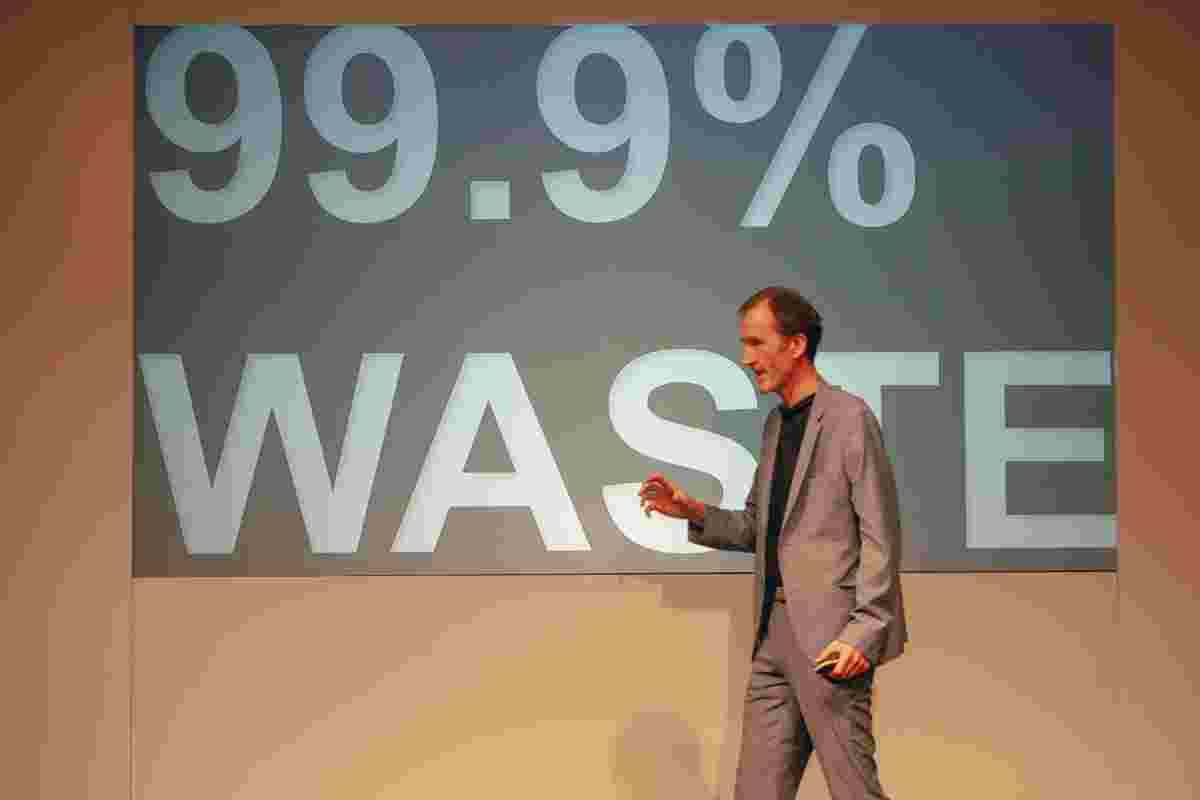 Gerry McGovern onstage at Camp Digital. The slide on screen reads "99.9% waste".