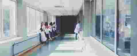 A long hallway with windows on both sides and Doctors And Patients stood against the side